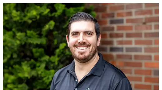 Chiropractor Kyle Zabst smiling in front of a brick wall.